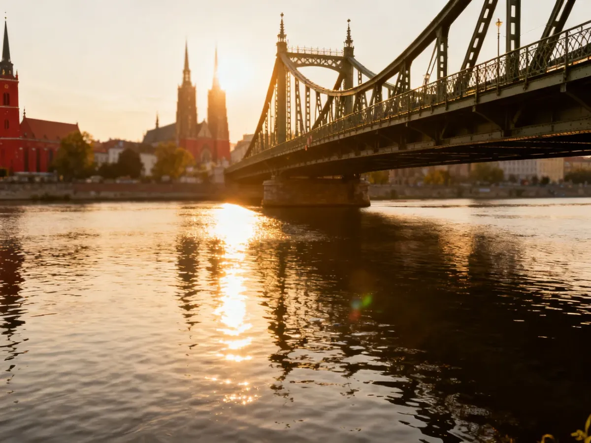 Zabytkowy stalowy most we Wrocławiu o zachodzie słońca z widokiem na gotycką architekturę nad Odrą.